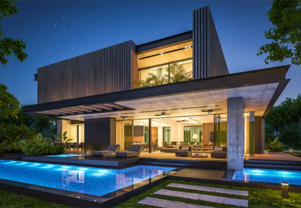 Modern house sits illuminated at night, showcasing a pool.